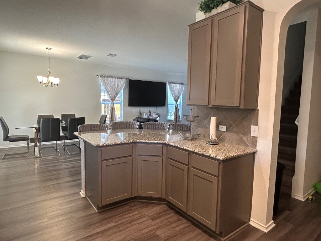 420 Lt. Rusty Jarrell, TX 76537 - Photo 9 of 17 Kitchen with light stone counters, dark wood-style flooring, a peninsula, hanging light fixtures, and a chandelier
