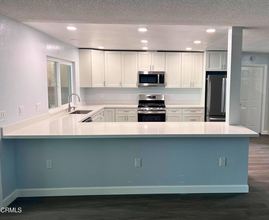 10945 Kings Road Ventura, CA 93004 - Photo 6 of 19 a kitchen with stainless steel appliances a sink a stove a microwave a refrigerator and white cabinets