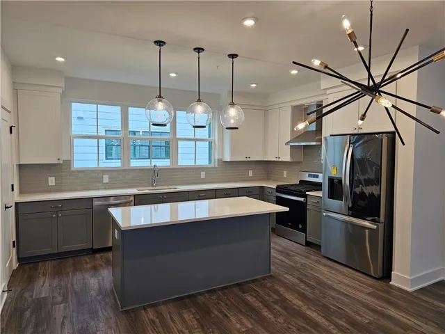a kitchen with stainless steel appliances granite countertop a sink a stove and a wooden floors
