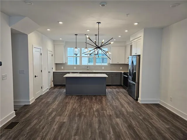 a kitchen with stainless steel appliances a refrigerator and a wooden floor