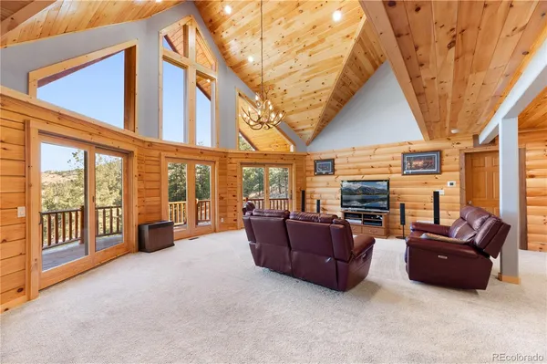 a living room with furniture a flat screen tv and floor to ceiling windows