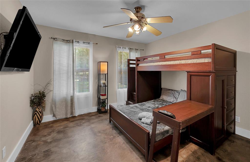 37 Bluebonnet Loop Morgan's Point Resort, TX 76513 - Photo 26 of 38 Room featuring neutral wall tones, two windows with white blinds and sheer curtains, a ceiling fan with integrated lighting, and dark-toned flooring