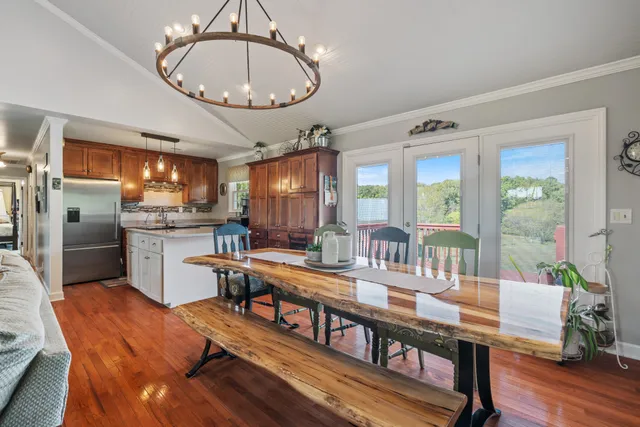 a very nice looking dining room with kitchen island furniture a chandelier a large window and stainless steel appliances
