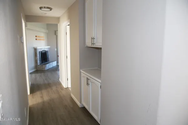 a view of a hallway with wooden floor and a bathroom