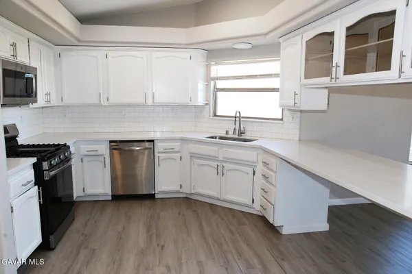a kitchen with granite countertop white cabinets sink and stainless steel appliances