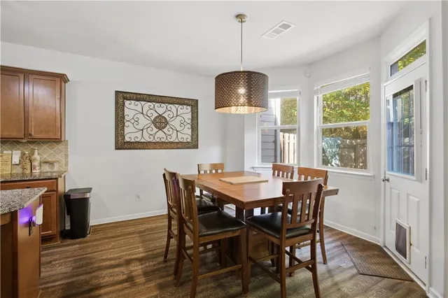 a open kitchen with stainless steel appliances granite countertop a refrigerator a sink dishwasher a dining table and chairs with wooden floor