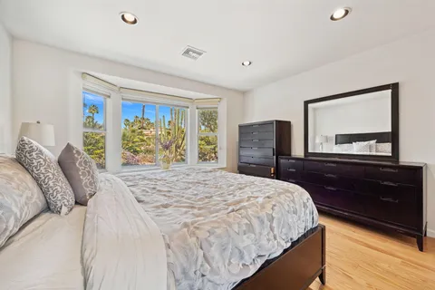 a bedroom with a bed a dresser next to a window