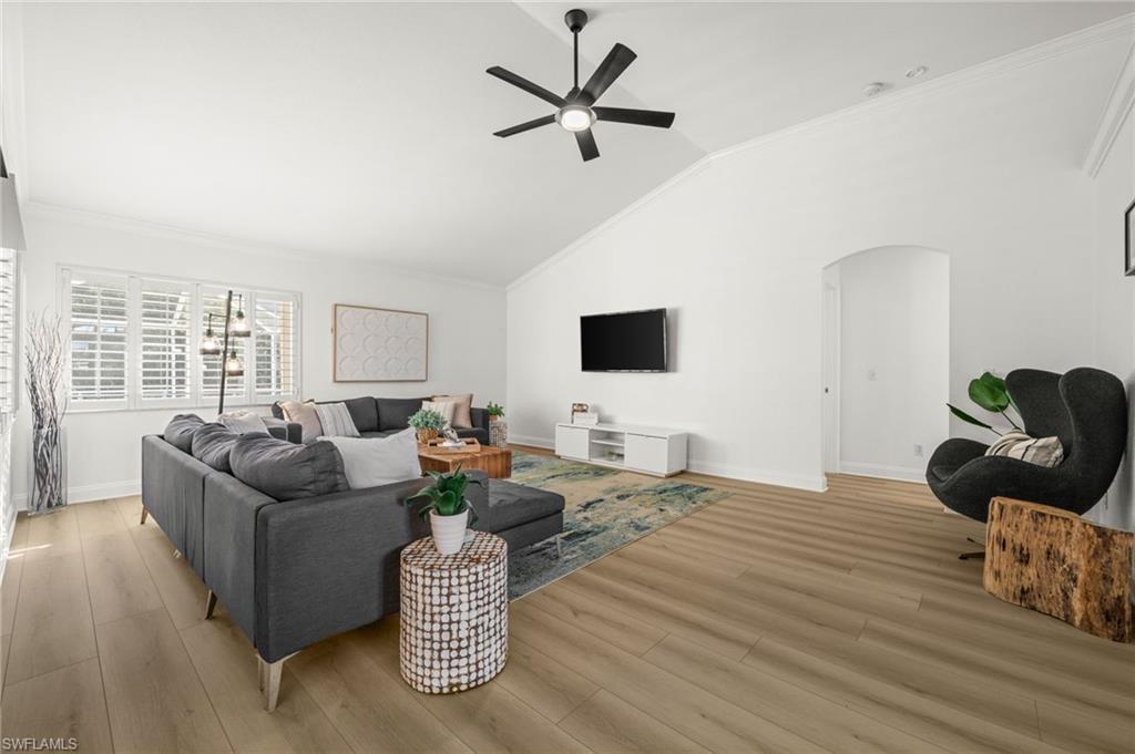 4 Colonial Drive Naples, FL 34112 - Photo 13 of 42 Living room featuring ornamental molding, lofted ceiling, a ceiling fan, arched walkways, and light wood-style floors