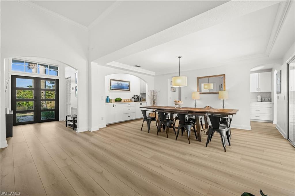 4 Colonial Drive Naples, FL 34112 - Photo 15 of 42 Dining room featuring arched walkways, plenty of natural light, crown molding, light wood-style floors, and a high ceiling