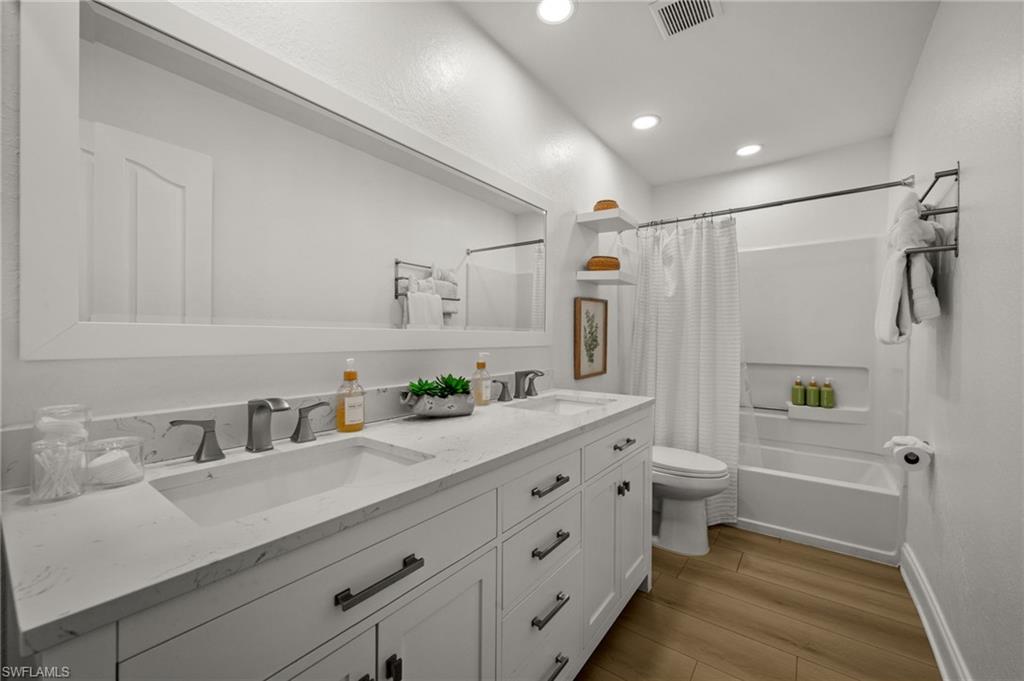 4 Colonial Drive Naples, FL 34112 - Photo 23 of 42 Bathroom with double vanity, shower / bath combination with curtain, light wood-style flooring, and recessed lighting
