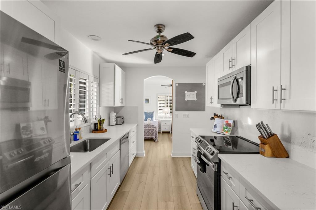 4 Colonial Drive Naples, FL 34112 - Photo 9 of 42 Kitchen featuring stainless steel appliances, ceiling fan, white cabinetry, and light stone countertops
