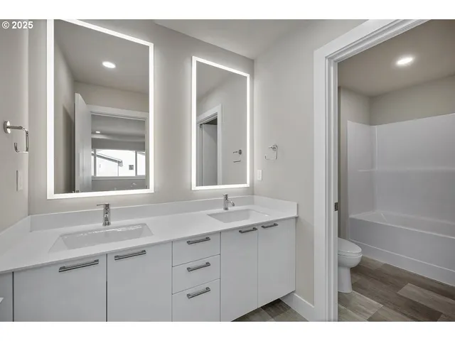 a bathroom with a granite countertop sink toilet a large mirror a bathtub and window