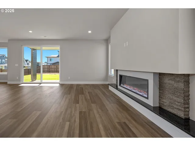 a view of an empty room with wooden floor and a fireplace