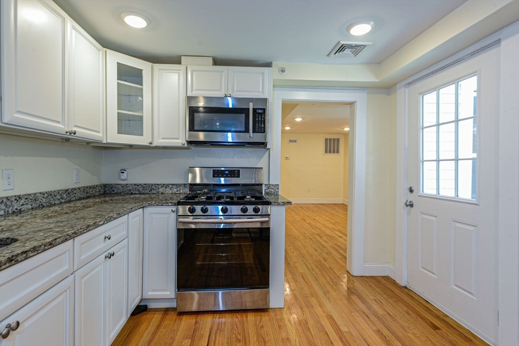 2 Mechanic Street, Unit 1 Newton, MA 02464 - Photo 4 of 14 a kitchen with stainless steel appliances granite countertop a stove and white cabinets
