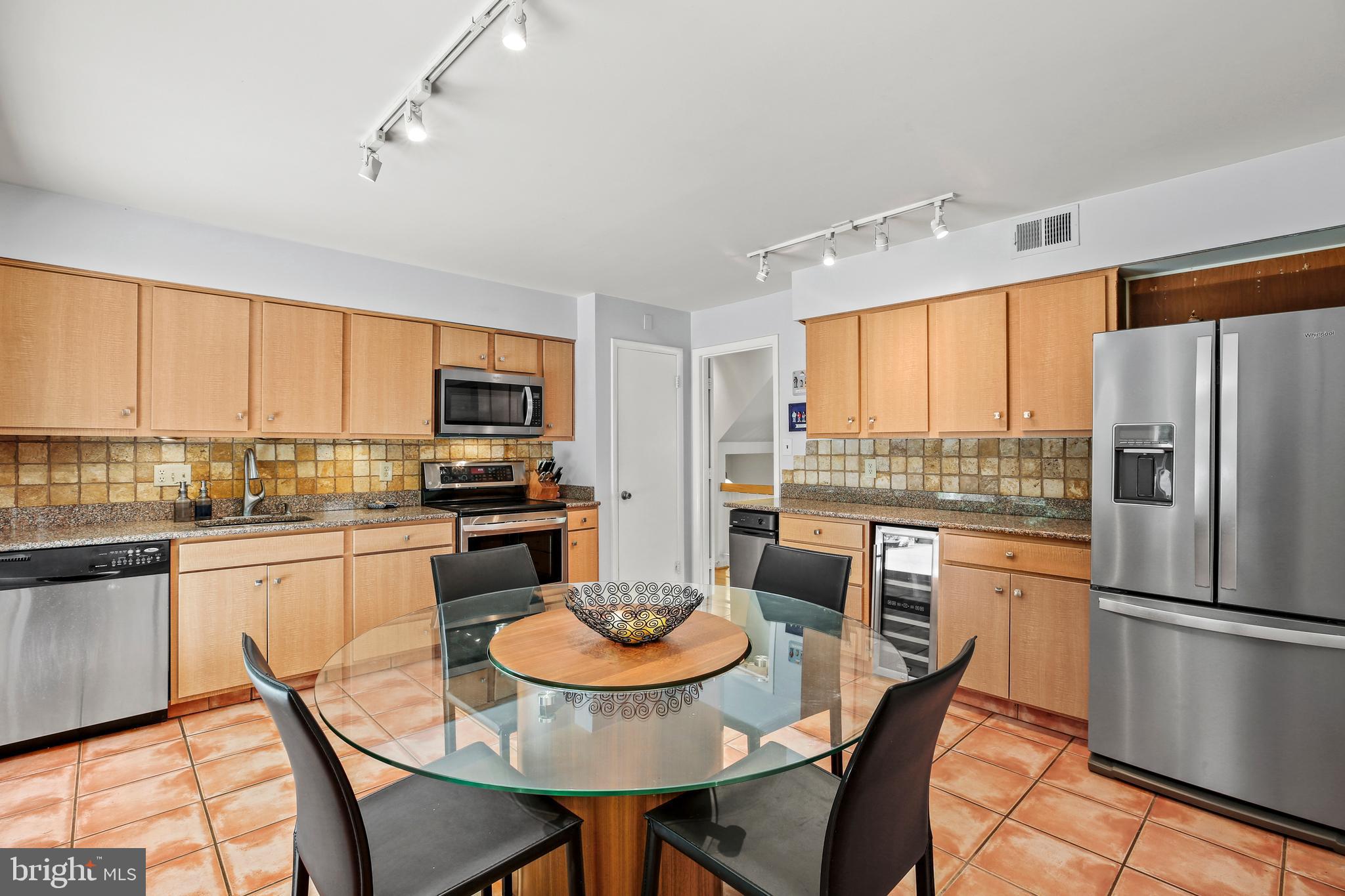 11212 Angus Place Potomac, MD 20854 - Photo 12 of 42 a kitchen with stainless steel appliances granite countertop a stove refrigerator dining table and chairs