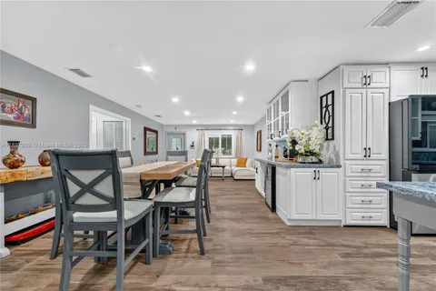 a dining hall with stainless steel appliances kitchen island granite countertop a dining table chairs and granite counter tops