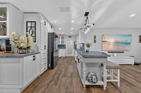 a large kitchen with kitchen island a counter top space a sink stainless steel appliances and cabinets