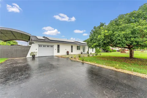 a view of a house with a yard and a large tree