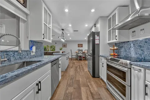 a kitchen with stainless steel appliances granite countertop a lot of counter space and wooden floors