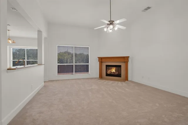 a view of an empty room with chandelier fan and fire place