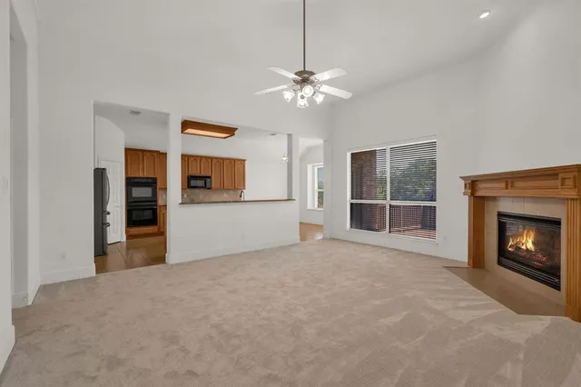 a view of a livingroom with a fireplace a ceiling fan and front door