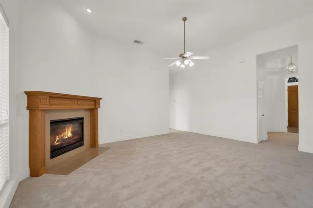 a view of an empty room with fan and fire place