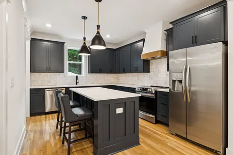 a kitchen with stainless steel appliances granite countertop a sink a stove a refrigerator and island