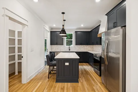 a kitchen with stainless steel appliances a refrigerator and a wooden floor