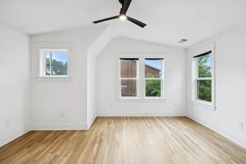 a view of empty room with wooden floor and fan