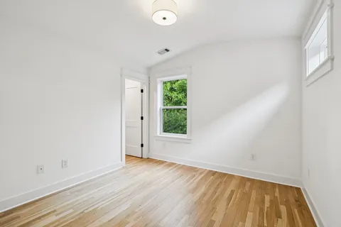 an empty room with wooden floor and windows