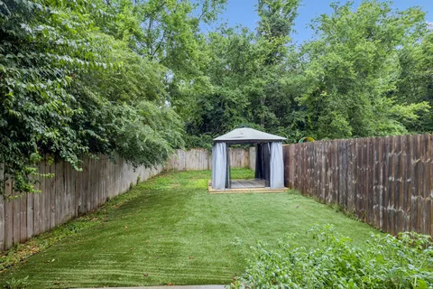a big yard with large trees and wooden fence