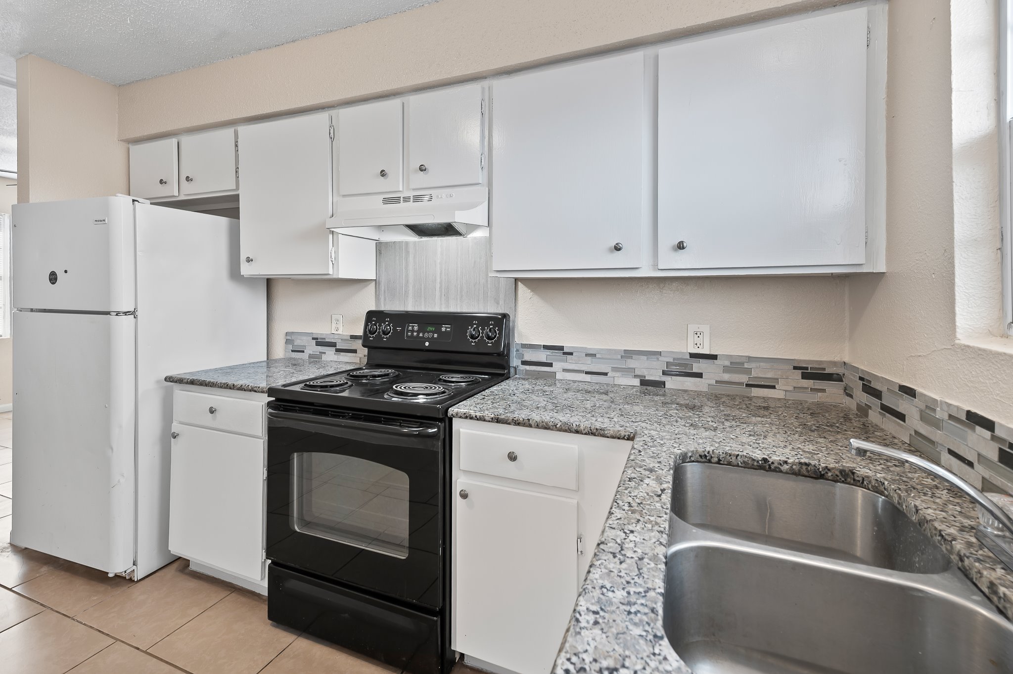 410 Old Thorndale Road, Unit D Taylor, TX 76574 - Photo 11 of 14 Kitchen featuring white cabinetry, granite-finish countertops, and a mosaic tile backsplash
