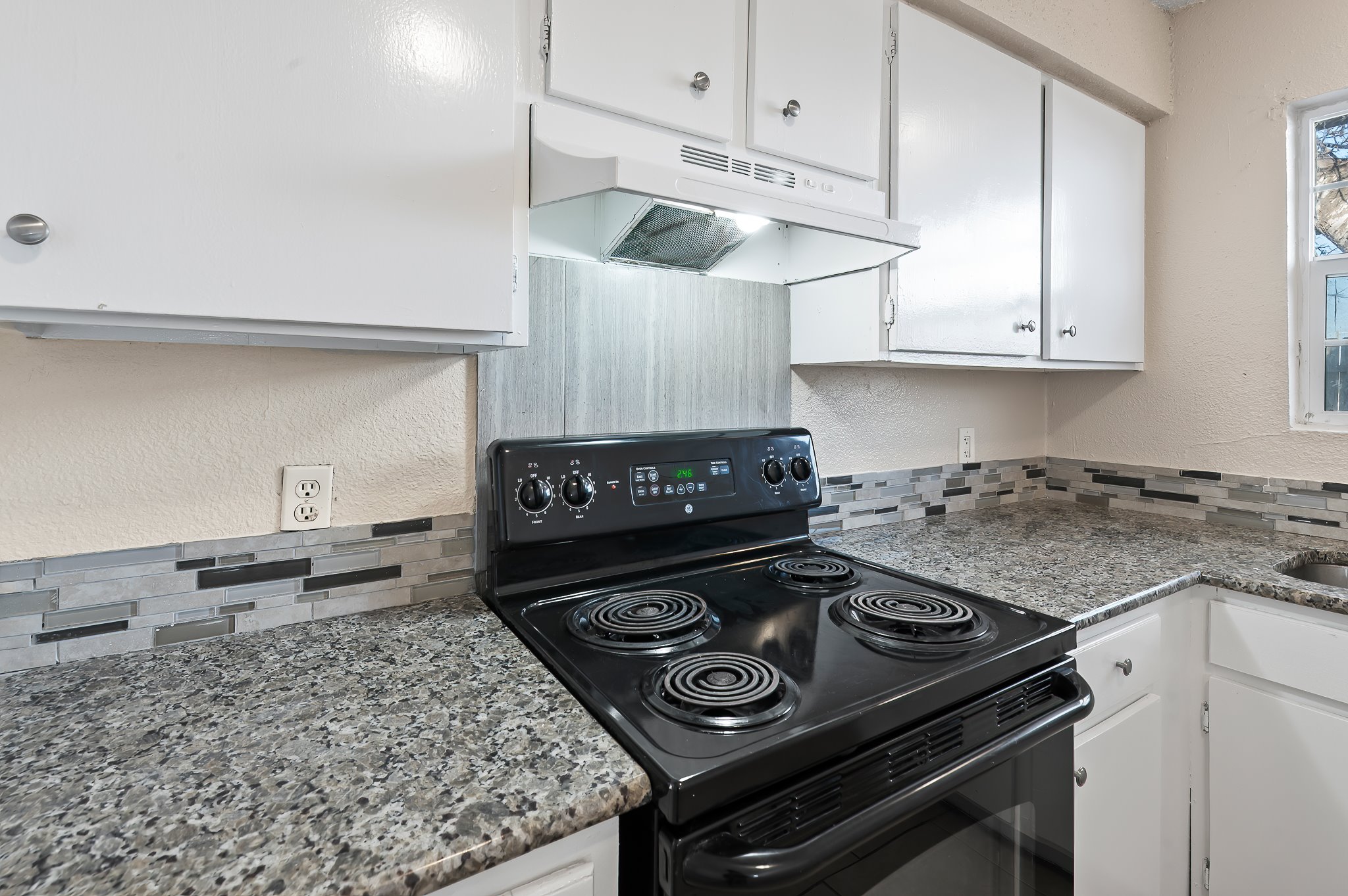 410 Old Thorndale Road, Unit D Taylor, TX 76574 - Photo 12 of 14 Kitchen featuring a black electric range, a mosaic tile backsplash, white cabinetry, and a granite-style countertop