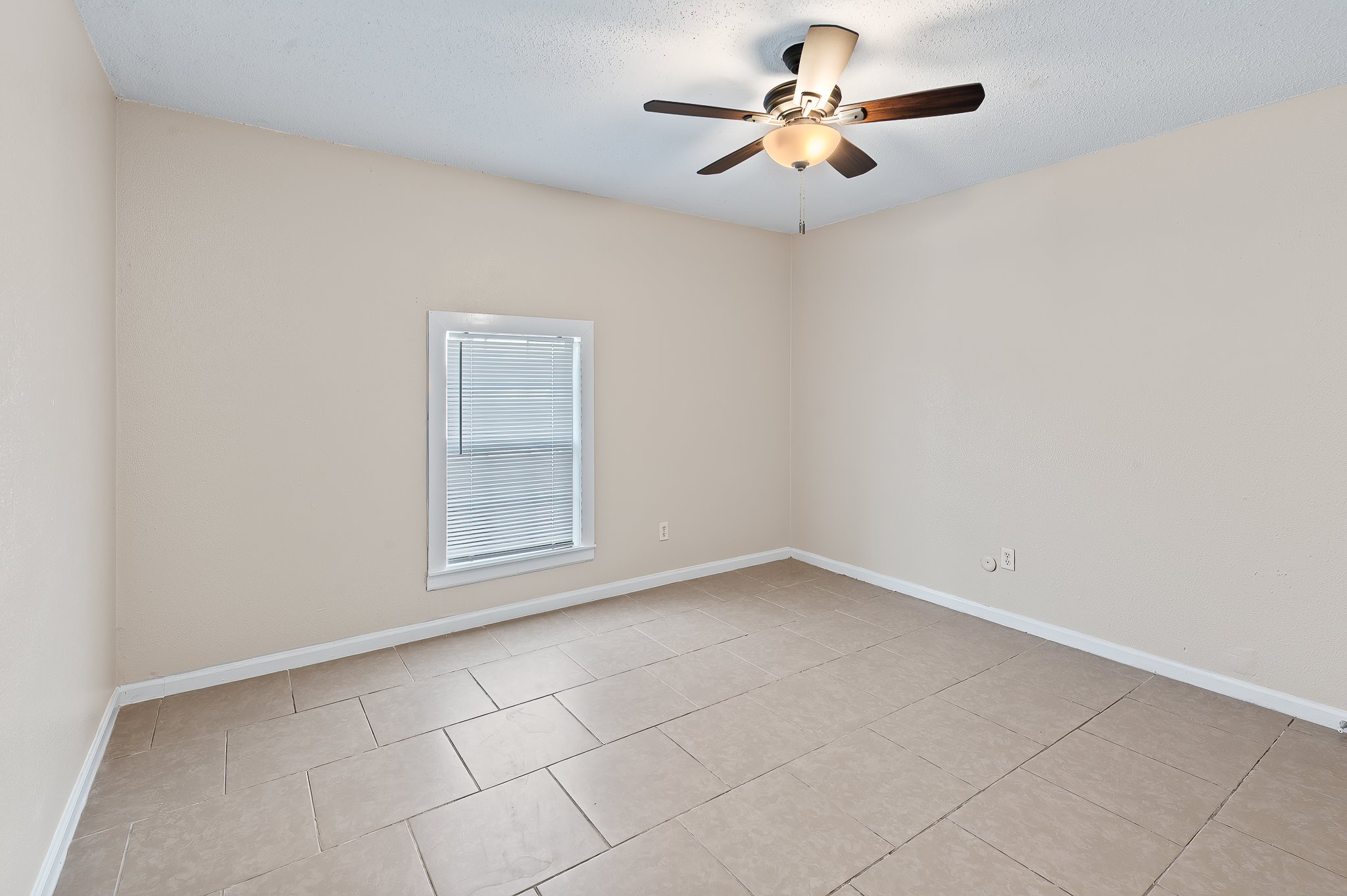 410 Old Thorndale Road, Unit D Taylor, TX 76574 - Photo 13 of 14 Spacious room featuring neutral tone walls, large format ceramic tile flooring, and a ceiling fan with integrated lighting