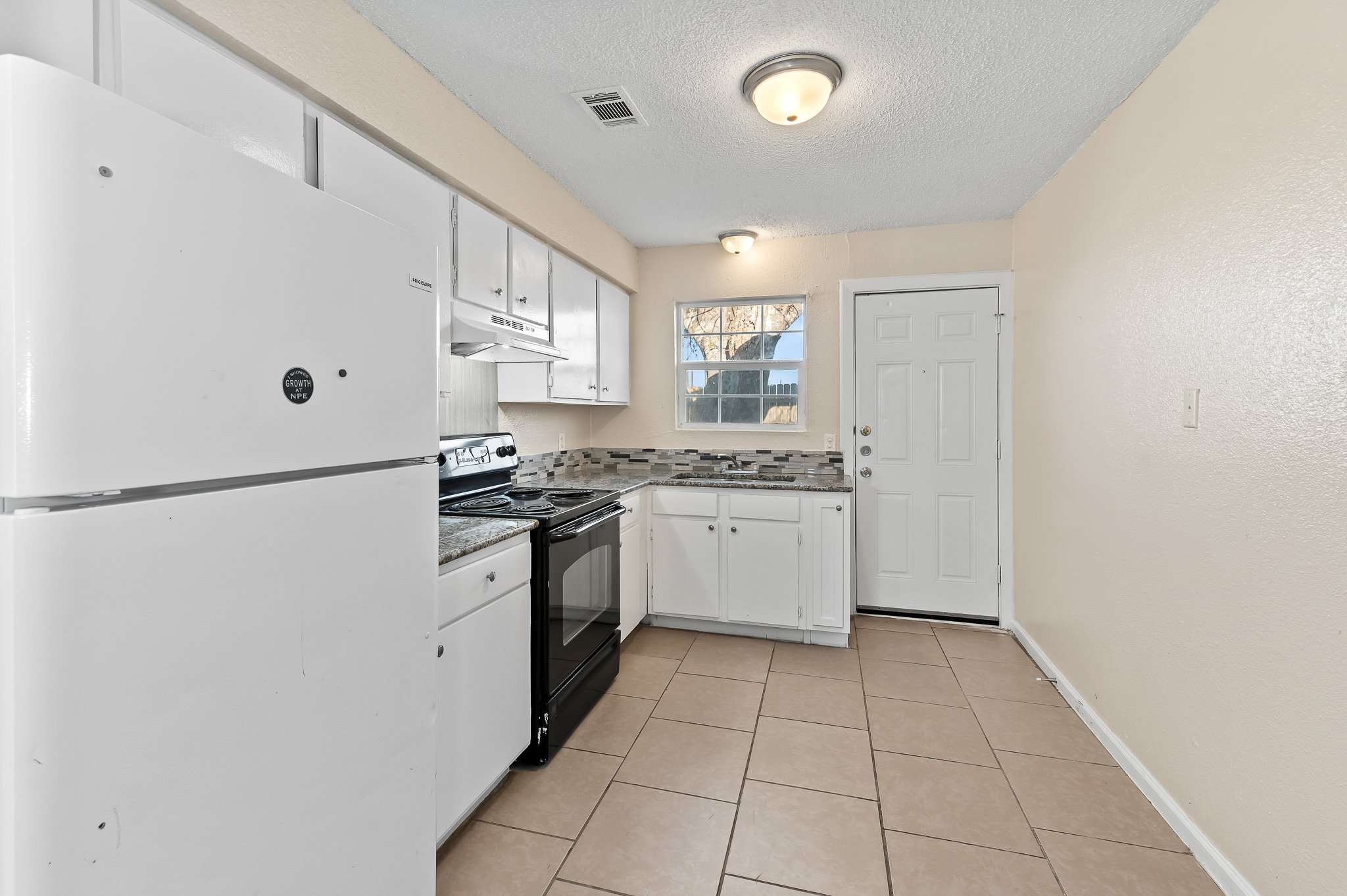 410 Old Thorndale Road, Unit D Taylor, TX 76574 - Photo 7 of 14 Kitchen featuring white cabinetry, granite-look countertops, and a mosaic tile backsplash