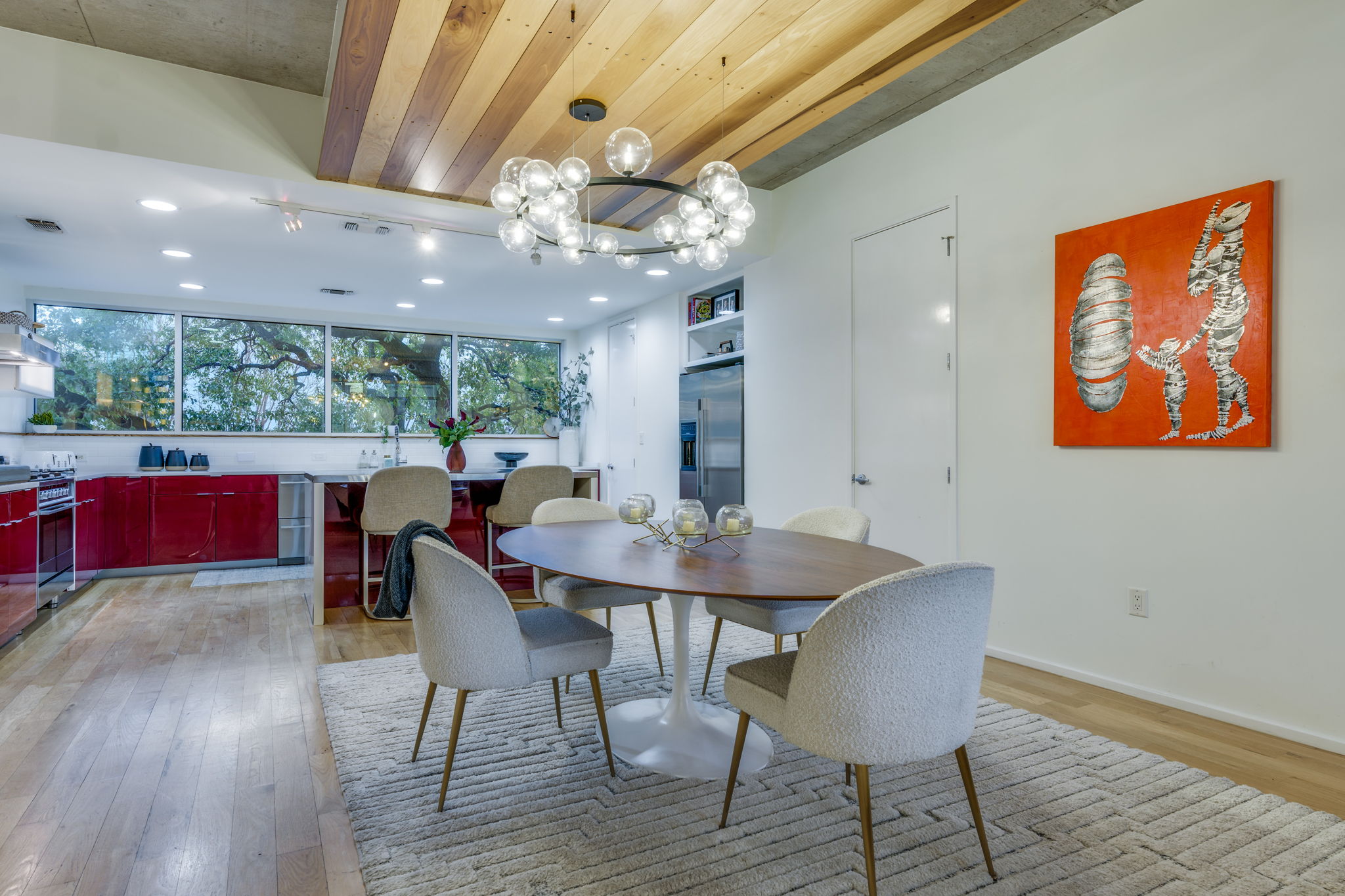 2301 South 5th Street, Unit 5 Austin, TX 78704 - Photo 10 of 39 A striking bubble light chandelier illuminates this open-plan dining area with rich hardwood floors and an adjacent modern kitchen.