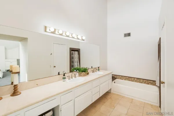 a bathroom with a double vanity sink mirror and bathtub