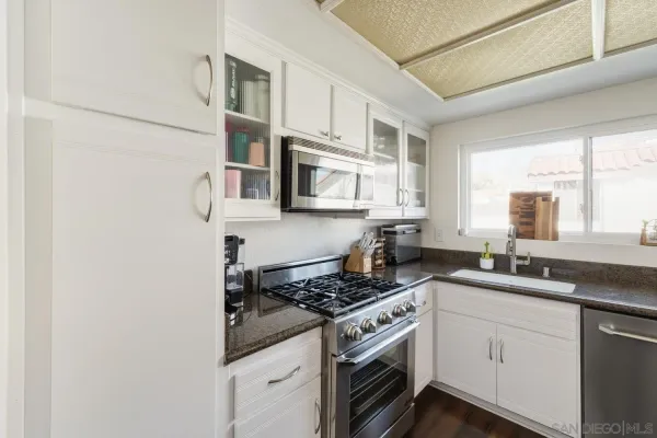 a kitchen with stainless steel appliances granite countertop a sink stove oven and white cabinets