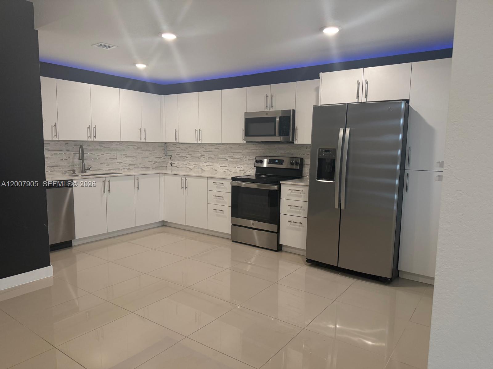 25664 Southwest 143rd Path, Unit 25664 Homestead, FL 33032 - Photo 2 of 17 a kitchen with stainless steel appliances granite countertop a refrigerator and a stove top oven