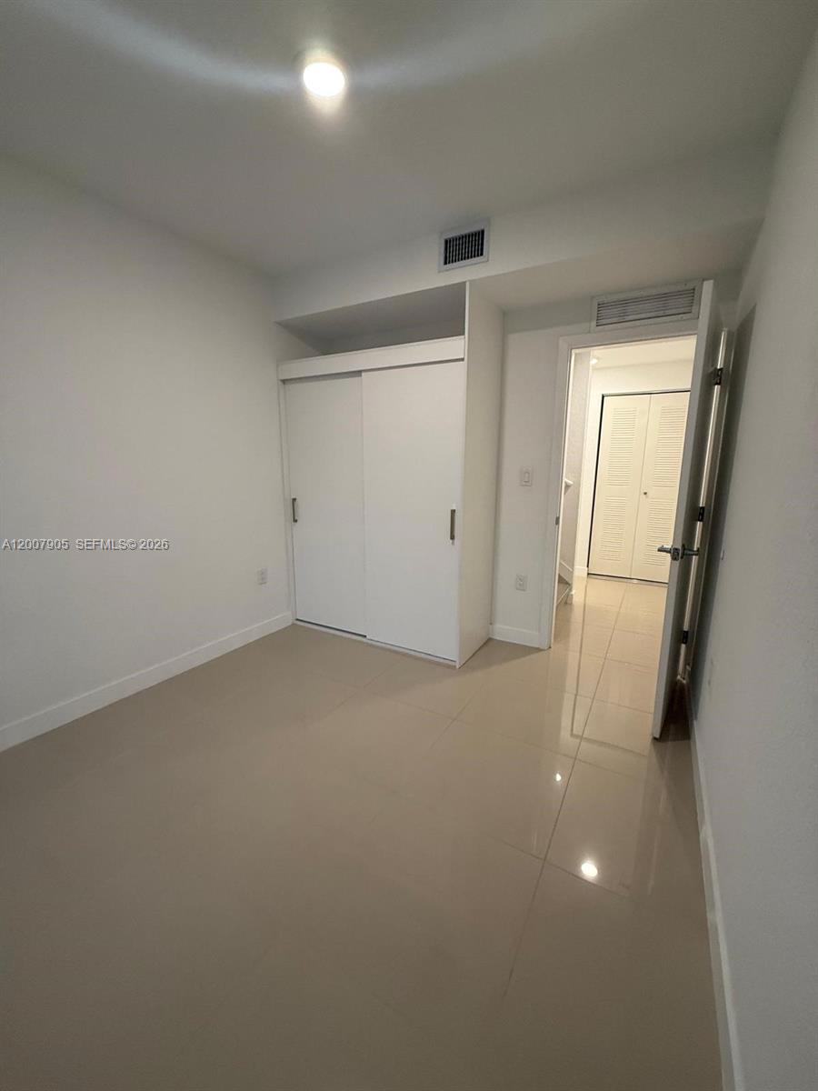25664 Southwest 143rd Path, Unit 25664 Homestead, FL 33032 - Photo 3 of 17 an empty room with wooden floor and mirror