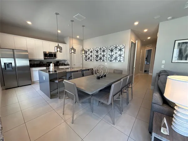 a kitchen with stainless steel appliances kitchen island granite countertop a table chairs microwave and sink