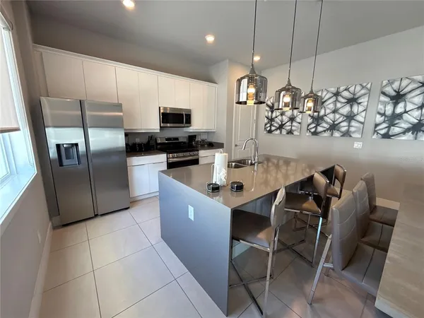 a kitchen with stainless steel appliances a refrigerator a stove a sink a dining table and chairs with wooden floor