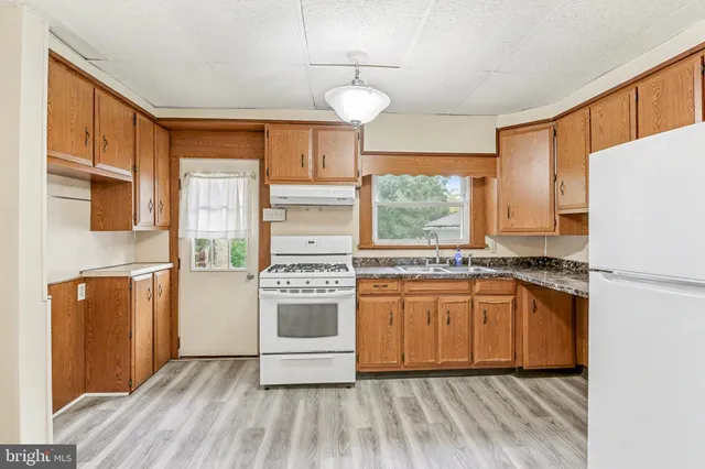 a kitchen with stainless steel appliances granite countertop a refrigerator a stove a sink and a window