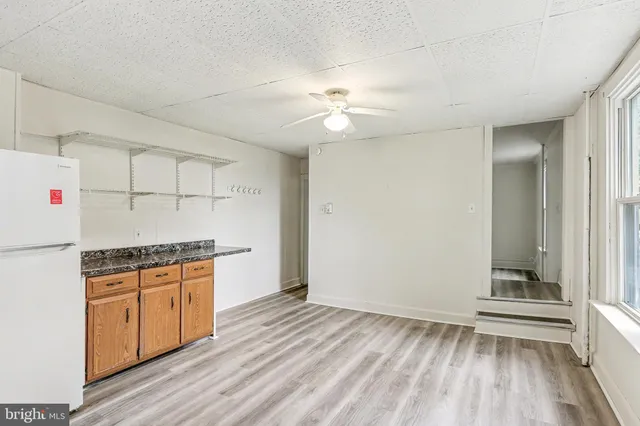 a kitchen with granite countertop a stove a sink and a refrigerator with wooden floors