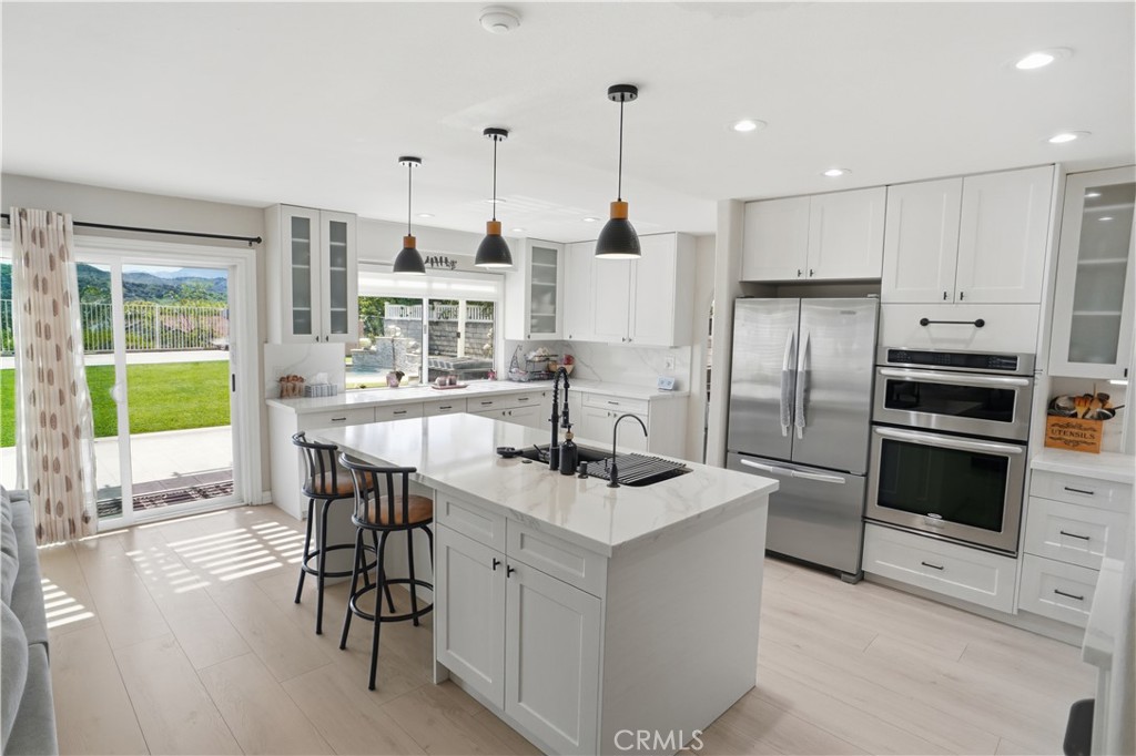 25550 Longfellow Place Stevenson Ranch, CA 91381 - Photo 6 of 30 a kitchen with kitchen island a large counter top space appliances and a view of living room