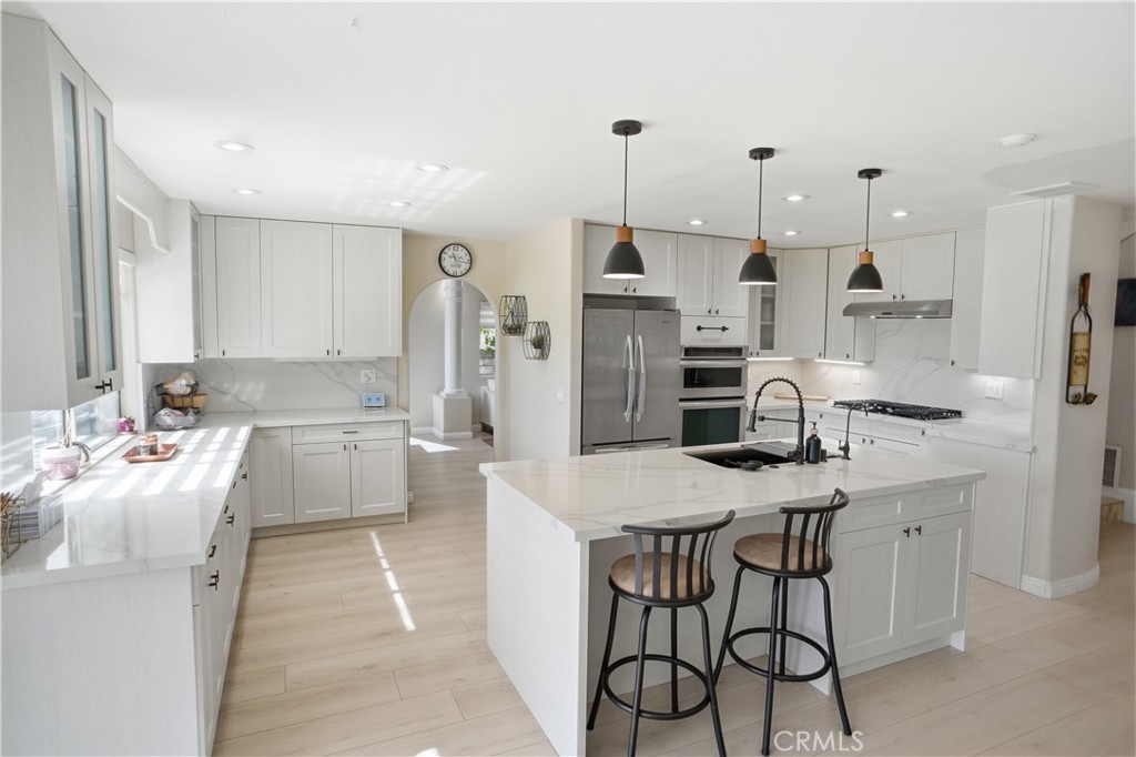 25550 Longfellow Place Stevenson Ranch, CA 91381 - Photo 7 of 30 a large kitchen with stainless steel appliances kitchen island granite countertop a sink and cabinets