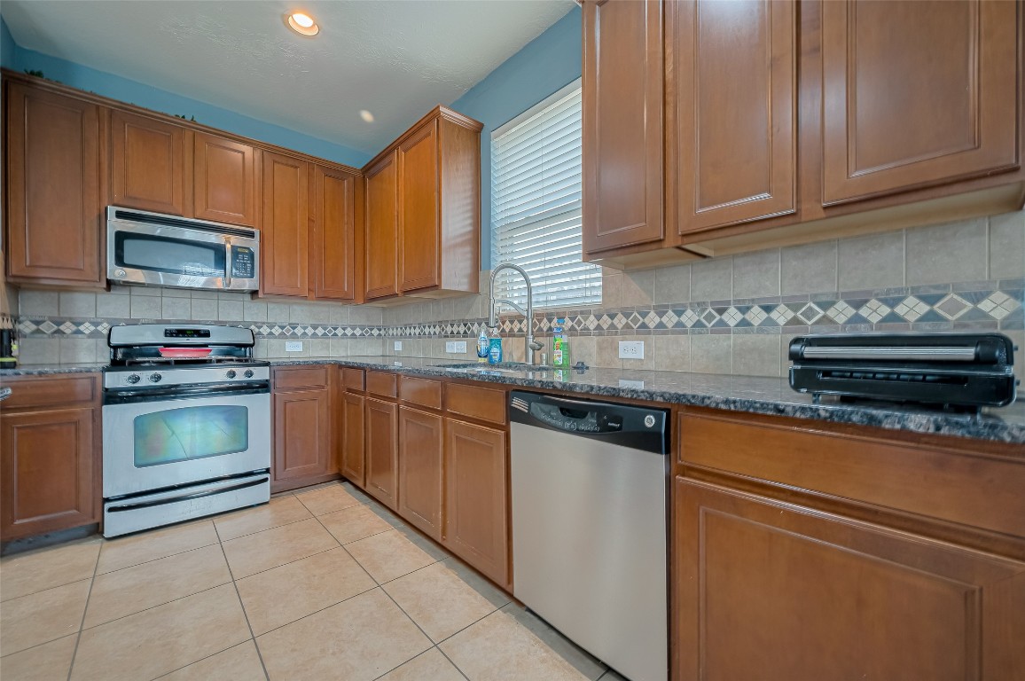 1703 Macclesby Lane Houston, TX 77049 - Photo 12 of 41 a kitchen with granite countertop a stove top oven microwave and cabinets