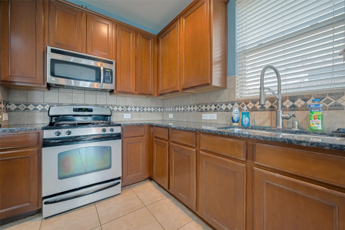 1703 Macclesby Lane Houston, TX 77049 - Photo 13 of 41 a kitchen with stainless steel appliances granite countertop a sink stove and microwave