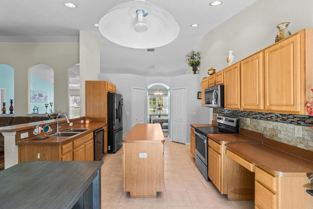 16038 Malden Road Weeki Wachee, FL 34614 - Photo 6 of 40 a large kitchen with stainless steel appliances a stove a sink dishwasher and cabinets with wooden floor