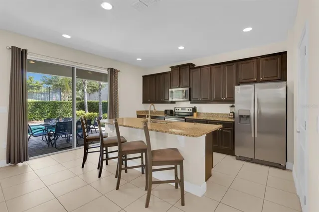 a kitchen with stainless steel appliances granite countertop a stove a refrigerator a kitchen island a table and chairs in it